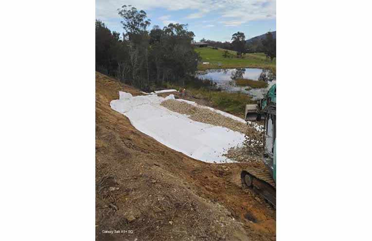 Excavators work to remediate the 70 metre long landslip site at Flame Tree Road, Valla, in early July, by moving earth to create a sloped surface.
Photos: Supplied by NVC.