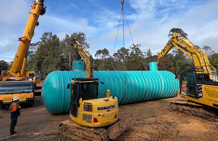 A crane lifts the first 106,000-litre emergency storage tank off the truck and into position.