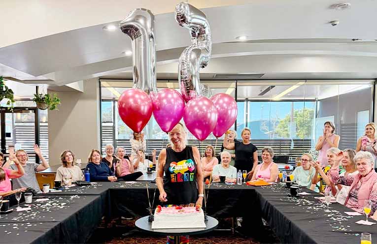 Kerri Mergan cut a cake celebrating 15 years teaching Zumba, surrounded by members of her group. Photo: Gai McKay.